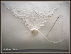 an embroidered white pillow with a needle and thread