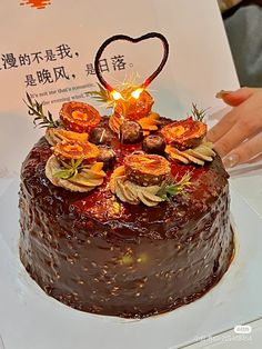 a chocolate cake with orange flowers on top is being held up by someone's hand