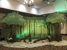 an indoor stage set up with trees and animals