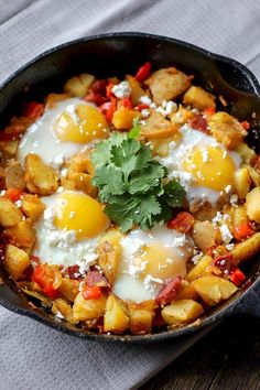 a skillet filled with eggs and vegetables on top of a cloth next to a fork