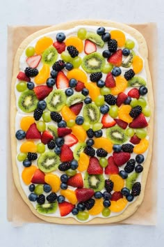 a pizza with fruit toppings on it sitting on top of a piece of parchment paper