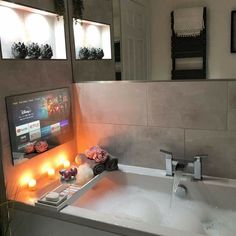 a bathroom sink with candles on the side and a television in the corner above it