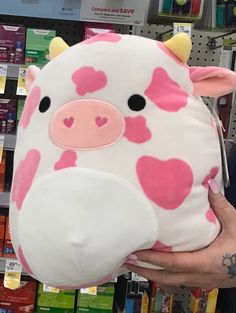 a person holding a stuffed cow in front of a store shelf with other items on display