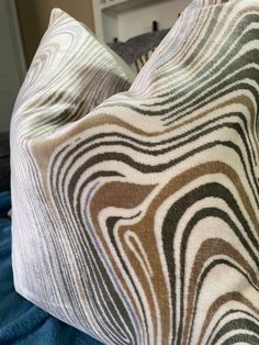 two zebra print pillows sitting on top of a blue bed sheet covered in white and brown sheets