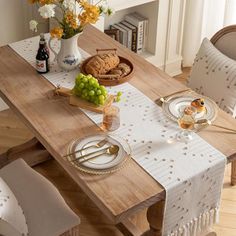 a wooden table topped with plates and glasses filled with food next to a vase full of flowers