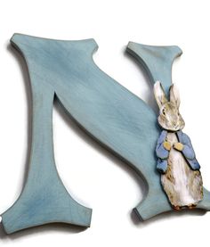 a wooden letter k with a rabbit on it's back and the letter k painted in blue