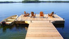 a small boat is docked at the end of a dock with chairs on it,