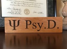 a wooden sign sitting on top of a table next to a framed document and vase