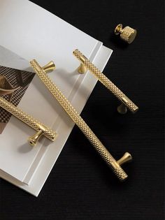 two pairs of gold colored metal handles on a black table next to a pair of bracelets