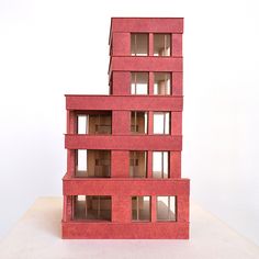 two red buildings are stacked on top of each other in front of a white wall