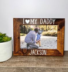 a wooden frame with the words, i love my daddy and a photo of a man holding a baby