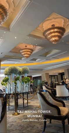 a hotel lobby with chandeliers, chairs and tables in the middle of it