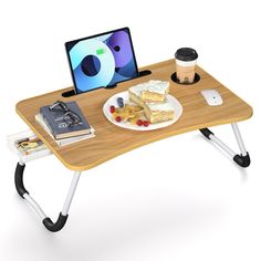 a wooden table topped with a plate of food and a laptop