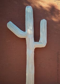 a large white cactus on the side of a building in front of a red wall