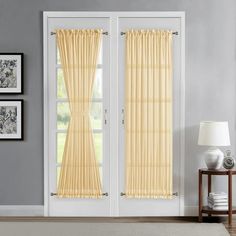 an open door with yellow curtains and pictures on the wall behind it in a living room