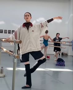 a man standing on top of a metal pole in front of ballet students wearing leotards