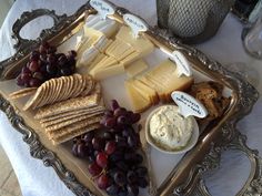 a tray with cheese, crackers and grapes on it