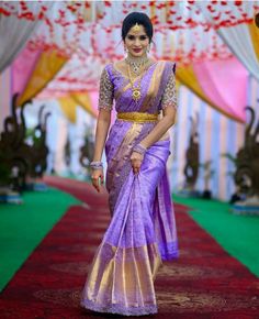 a woman in a purple and gold sari walks down the runway with her hand on her hip