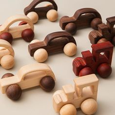 wooden toy trucks and cars are arranged in a circle on a white surface, with one car facing the camera