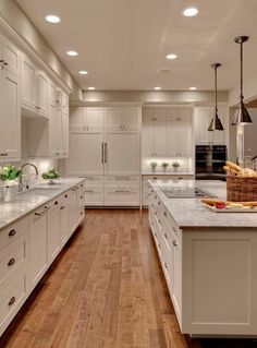 a large kitchen with white cabinets and wooden floors