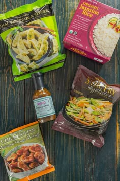 three bags of food sitting on top of a wooden table next to rice and seasoning