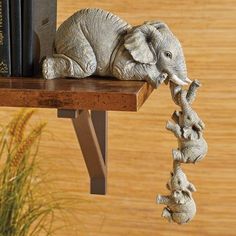 an elephant figurine sitting on top of a wooden shelf next to a book