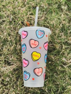 a cup with hearts on it sitting in the grass