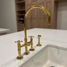 a kitchen sink with two brass faucets on the side and a white counter top