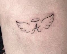 a small tattoo on the leg of a woman with an angel wing and letter a