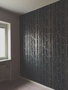 an empty room with a wallpapered tree pattern on the wall and a radiator