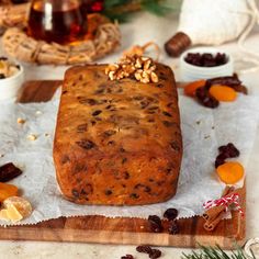 a loaf of bread sitting on top of a cutting board next to dried fruit and nuts