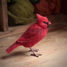 a red bird sitting on top of a wooden floor