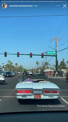 an old car is stopped at a red light on the road with another car behind it