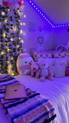 there is a laptop on the bed with stuffed animals and lights in the room behind it