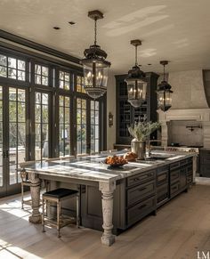 a large kitchen with an island in the middle and two chandeliers hanging from the ceiling