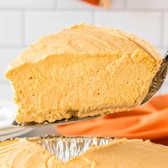 a piece of pumpkin cheesecake being lifted from a pie pan by a spatula