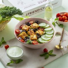 a bowl of salad with cucumbers, tomatoes and olives