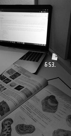 a laptop computer sitting on top of a desk next to an open book and magazine