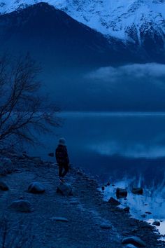 a man standing on top of a mountain next to a lake