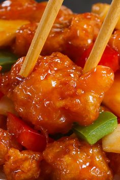 chicken and vegetables with chopsticks in a sauce on a plate, ready to be eaten