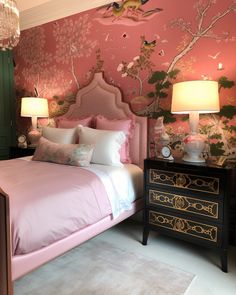 a bedroom with pink bedding and floral wallpaper, two lamps on either side of the bed