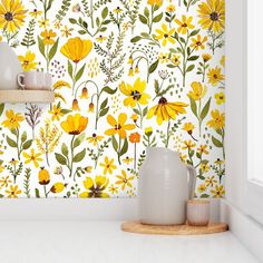 a kitchen with yellow flowers on the wall and white counter top, next to a window