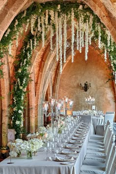 a long table is set up with white flowers and candles for an elegant wedding reception