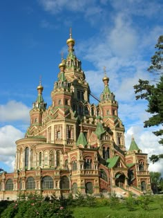 an old building with many spires on it's sides and green grass in the foreground