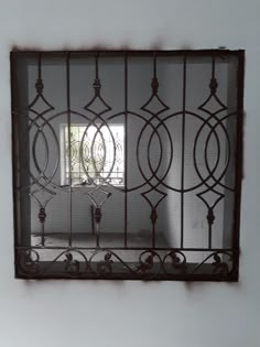 an iron window frame in the corner of a room with white walls and flooring