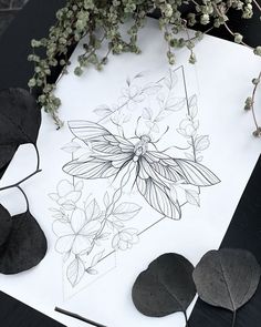 some leaves and flowers are sitting on a table next to a piece of white paper