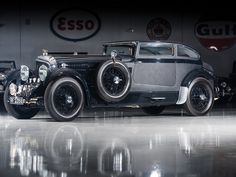 an antique car parked in front of a wall