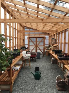 a room filled with lots of potted plants inside of wooden structures and windows on the ceiling