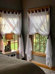 two windows with white drapes in a bedroom