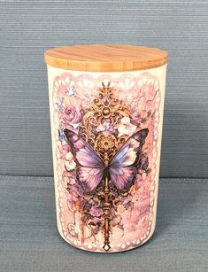 a ceramic container with a butterfly design on the lid and wooden stand in front of a blue wall